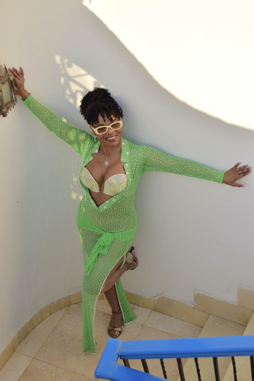 Kim Maria in green bellydance dress leaning against wall